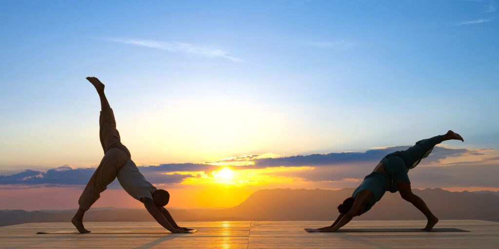 Couple silhouette practicing downward facing dog with leg lift yoga pose