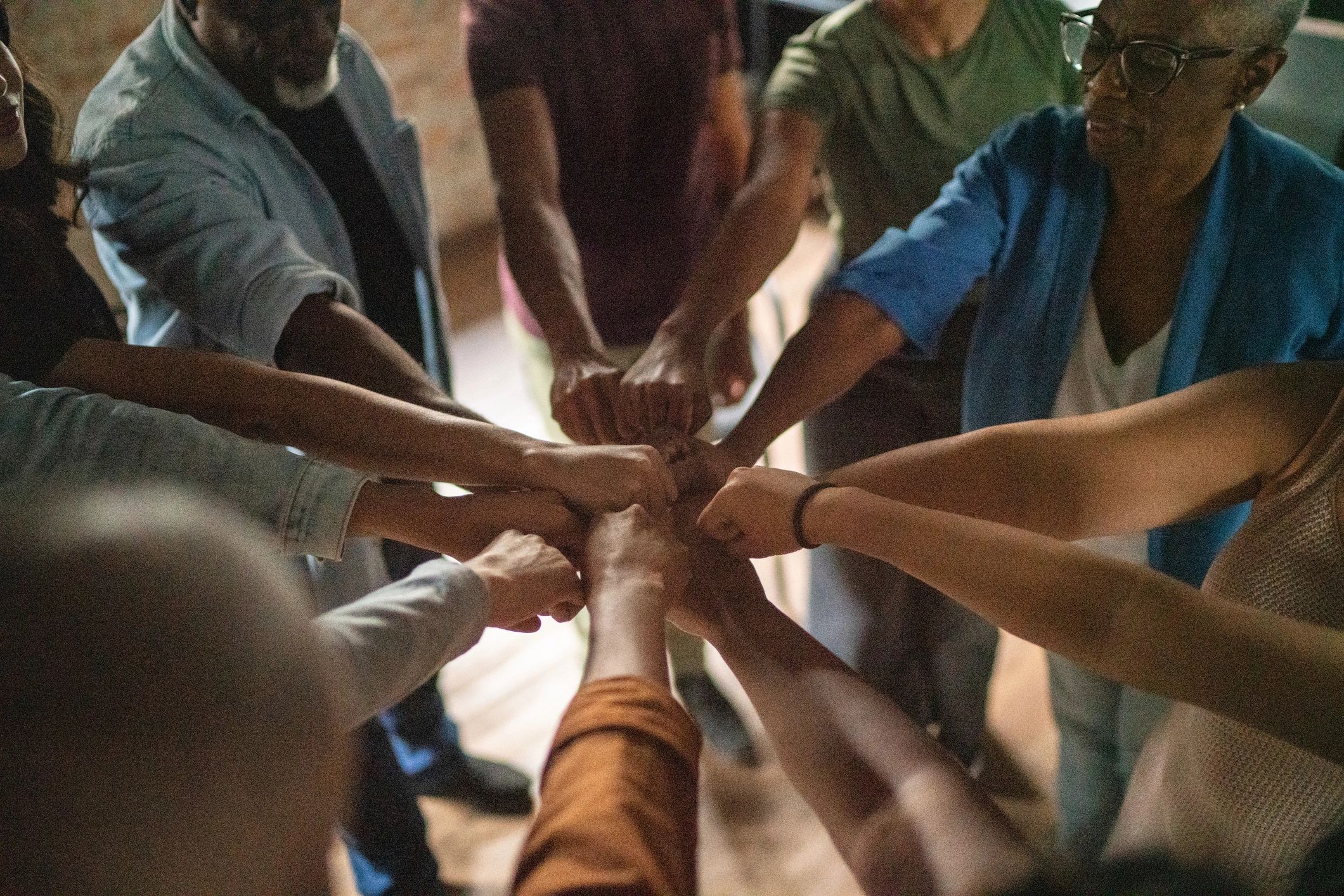Community members placing hands together in a circle