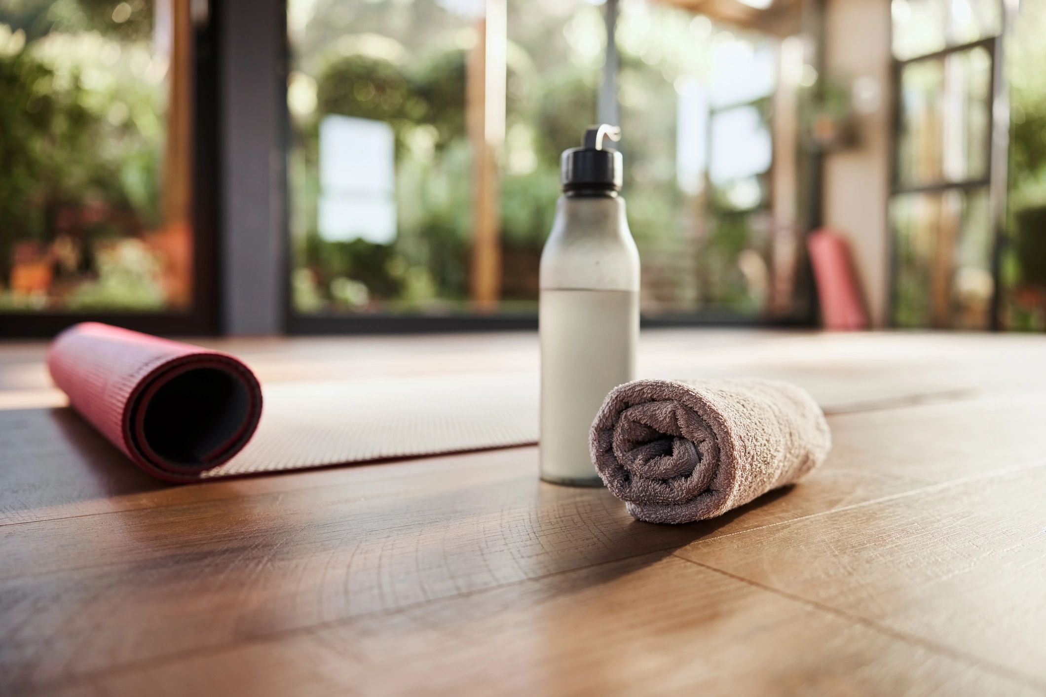 Water bottle, towel, and yoga mat on studio floor